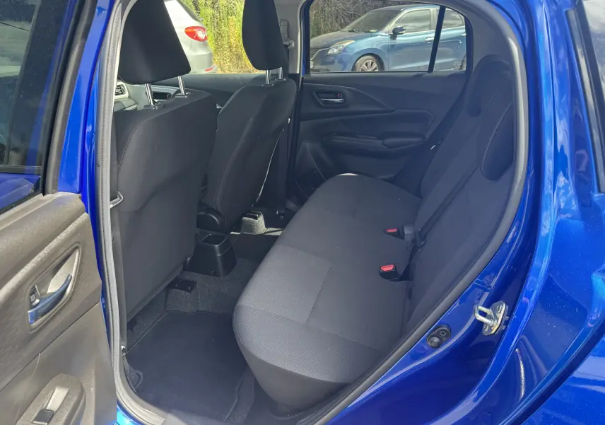 Vue intérieure côté gauche sur la banquette arrière noire d'une Suzuki Swift 1.2 Pack Hybrid bleu 2024 avec porte ouverte.