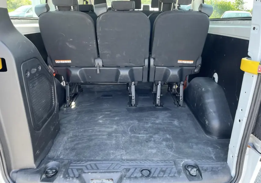 Vue arrière de l'habitacle du Ford Transit Custom blanc, montrant la banquette arrière et l'espace de chargement vide.