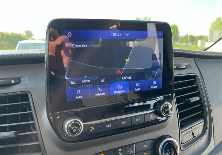 Écran tactile SYNC 3 avec navigation GPS visible sur le tableau de bord du Ford Transit Custom blanc.