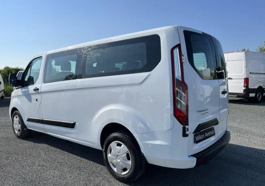 Vue 3/4 arrière droite du Ford Transit Custom Kombi blanc avec vitres latérales teintées et hayon vitré.