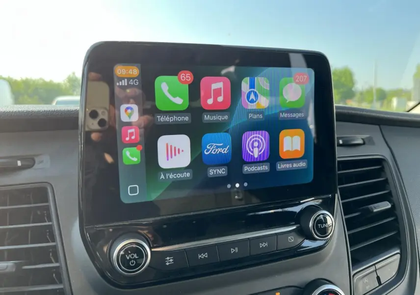 Écran tactile SYNC 3 au tableau de bord du Ford Transit Custom blanc, vue rapprochée de la console centrale.