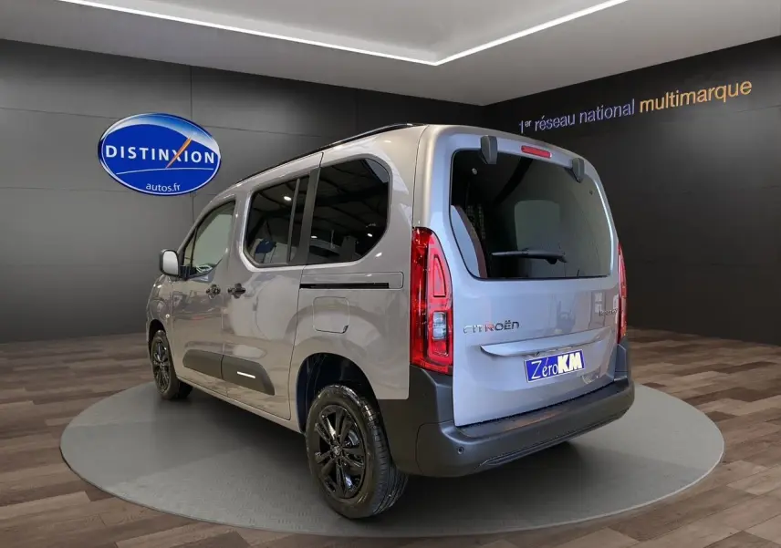 Vue 3/4 arrière droite d'un Citroën Berlingo gris Artense avec jantes noires dans un showroom.