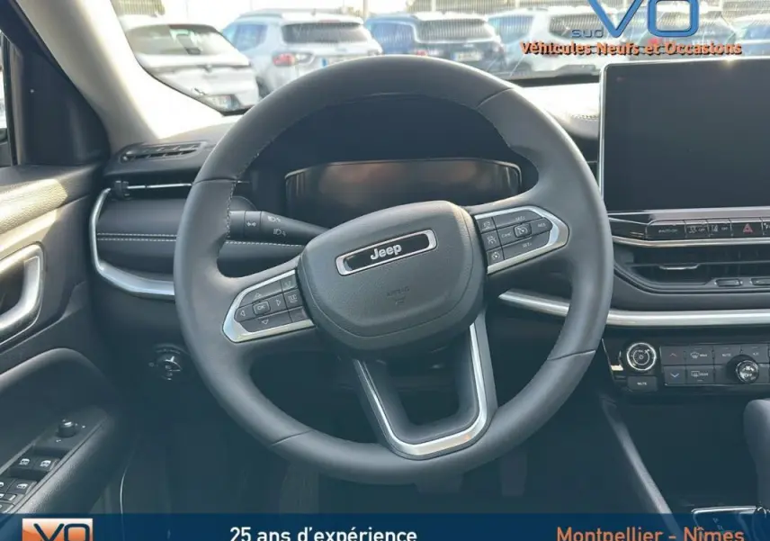 Vue intérieure centrée sur le volant du Jeep Compass noir 2024 avec tableau de bord et écran tactile visible.