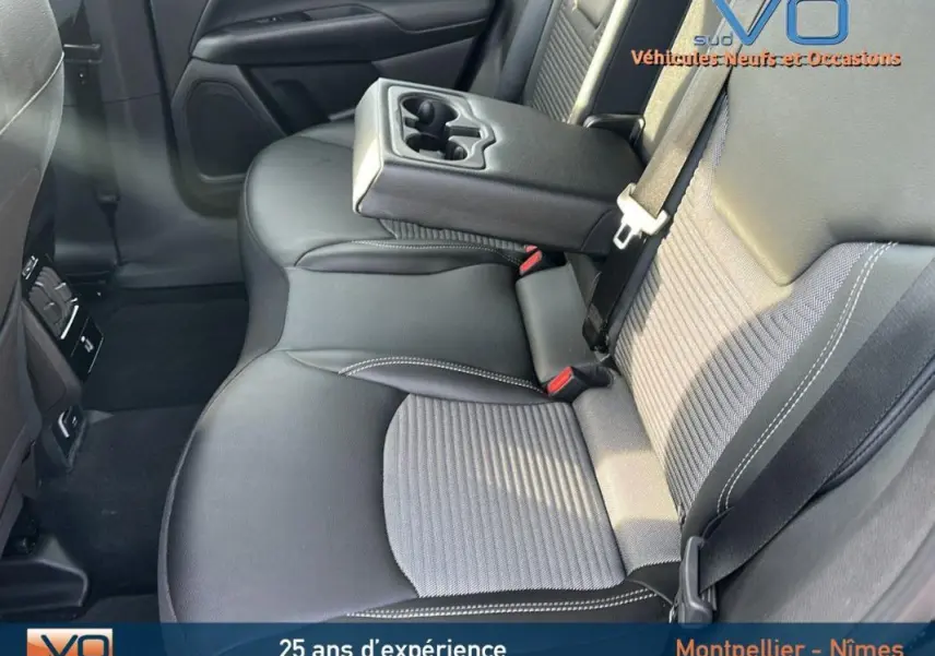 Vue intérieure des sièges arrière noirs du Jeep Compass 2024 avec accoudoir central relevé et ceintures visibles.