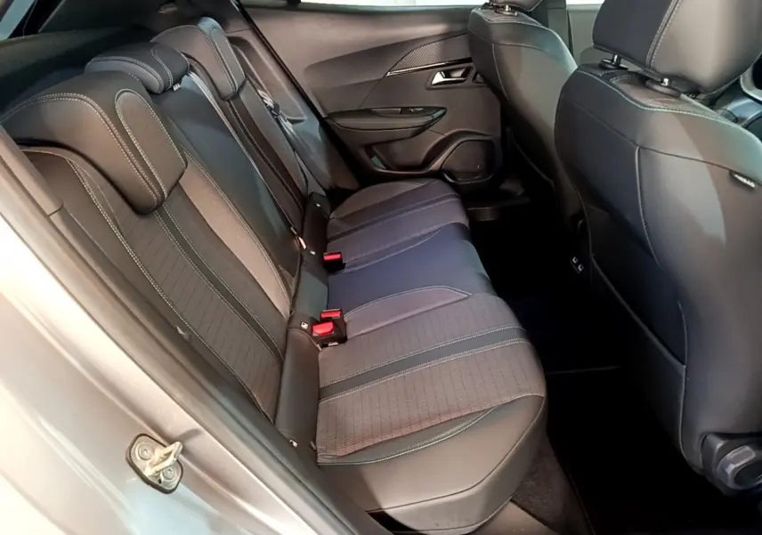Vue latérale intérieure des sièges arrière gris foncé du Peugeot 2008 PureTech 130, avec appuie-têtes et ceintures visibles.