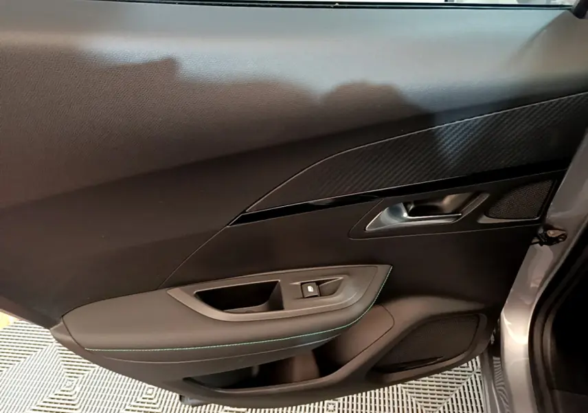Vue rapprochée de la porte côté gauche gris clair du Peugeot 2008 avec garniture noire et surpiqûres vertes.