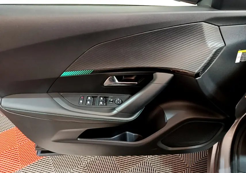 Intérieur côté conducteur du Peugeot 2008 gris clair 2021, avec panneau de porte noir et insert effet carbone.