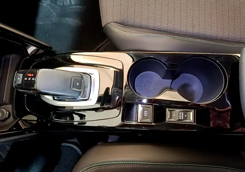 Vue plongeante sur la console centrale noire brillante du Peugeot 2008 gris clair, avec levier de vitesses automatique et porte-gobelets.