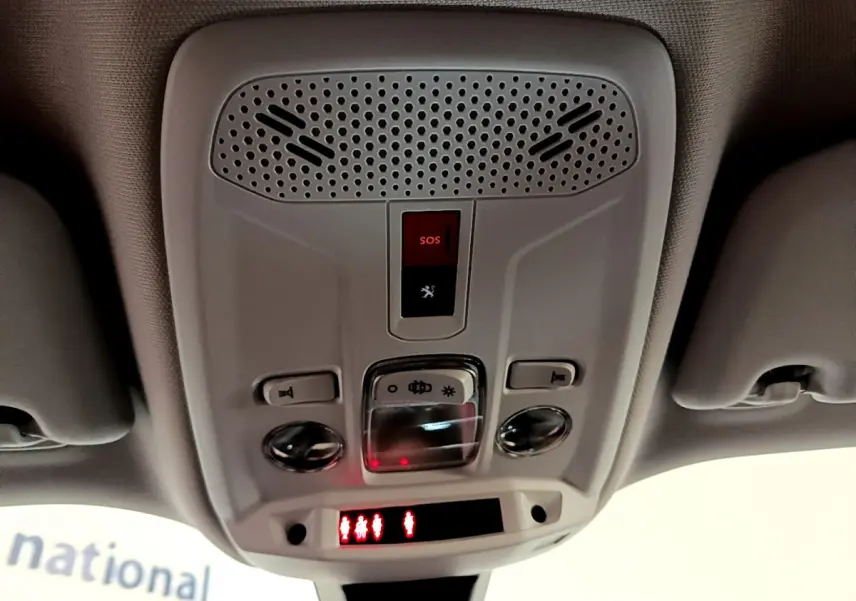 Plafonnier intérieur avec boutons SOS et éclairage, vue en contre-plongée dans un Peugeot 2008 gris clair de 2021.
