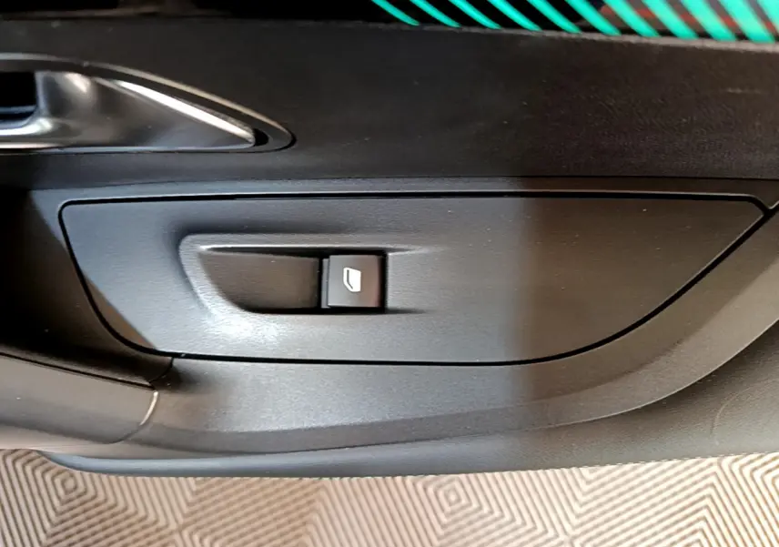 Bouton de commande de vitre électrique sur la porte intérieure noire d'un Peugeot 2008 gris clair, vue rapprochée.