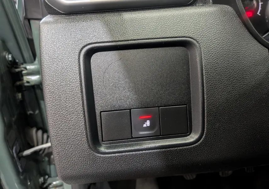 Gros plan sur le bouton de verrouillage centralisé du tableau de bord côté gauche du Dacia Duster kaki 2023.