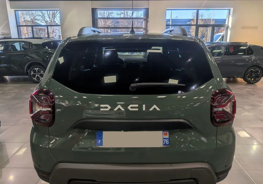Vue arrière d'un Dacia Duster 2023 kaki lichen en intérieur, avec logo DACIA bien visible sur le hayon.
