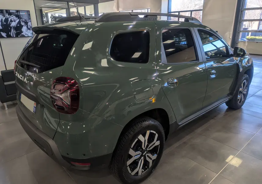 Vue 3/4 arrière droite du Dacia Duster 2023 kaki lichen, avec jantes alliage et détails noirs contrastants.