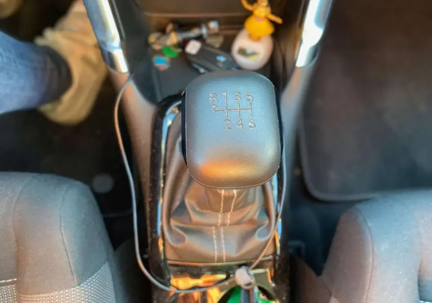 Gros plan sur le levier de vitesses manuel noir de la Citroën C3 Aircross gris foncé, avec console centrale et sièges partiellement visibles.