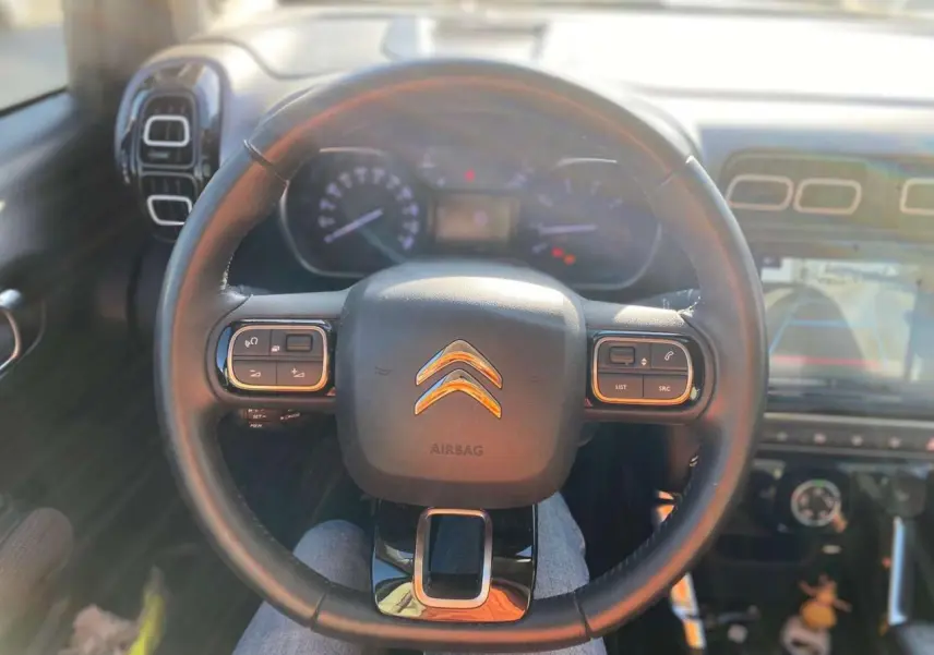 Vue intérieure centrée sur le volant du Citroën C3 Aircross 2024, avec commandes intégrées et tableau de bord visible.