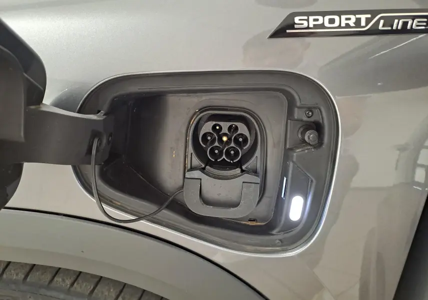 Prise de recharge ouverte côté gauche sur un Skoda Kodiaq Sportline gris graphite avec logo Sportline visible.
