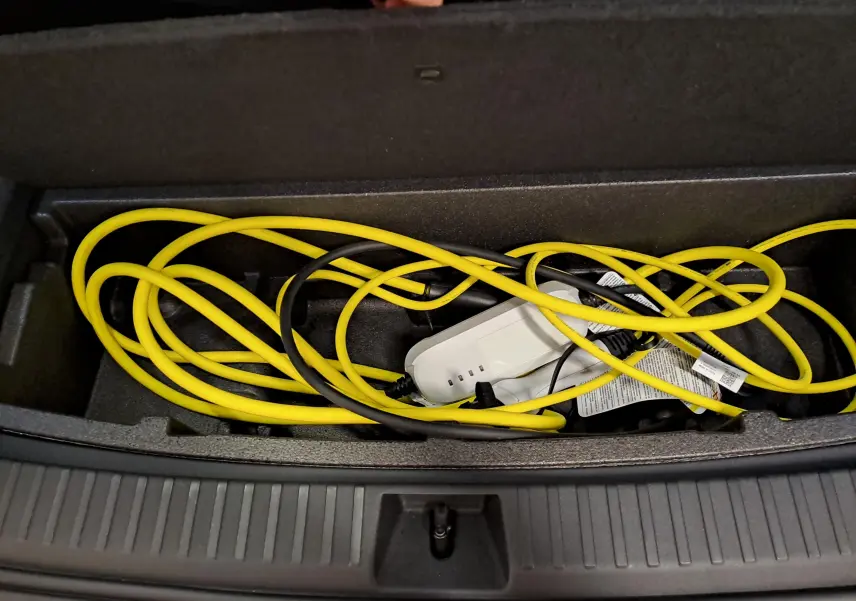Coffre ouvert montrant le câble de recharge jaune et noir du Skoda Kodiaq hybride rechargeable, détail intérieur du coffre.