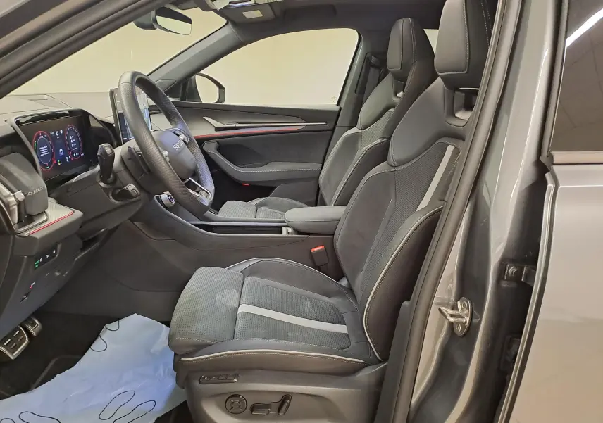 Vue intérieure côté conducteur du Skoda Kodiaq 2025 gris graphite, sièges sport noirs avec surpiqûres et tableau de bord digital.