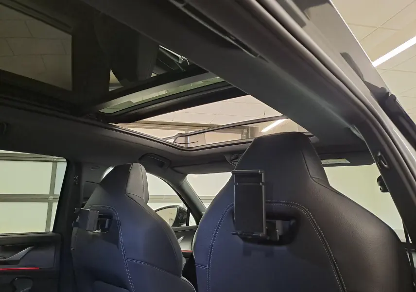 Vue intérieure arrière du Skoda Kodiaq gris graphite 2025, mettant en valeur le toit panoramique ouvrant et les appuie-têtes avec supports tablette.