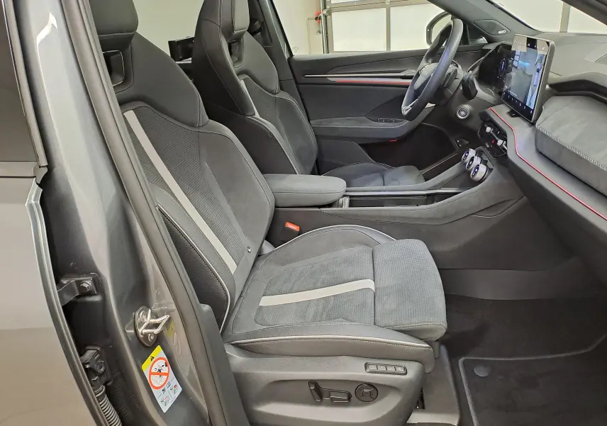 Vue intérieure côté gauche du Skoda Kodiaq gris graphite 2025, mettant en valeur les sièges sport et le tableau de bord moderne.