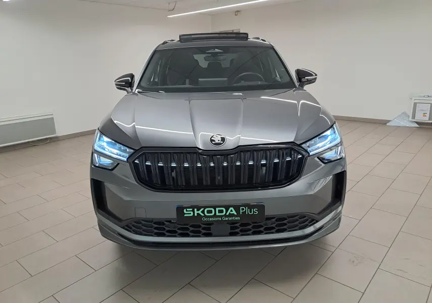 Vue frontale d'un Skoda Kodiaq gris graphite avec calandre noire et phares LED allumés en intérieur.