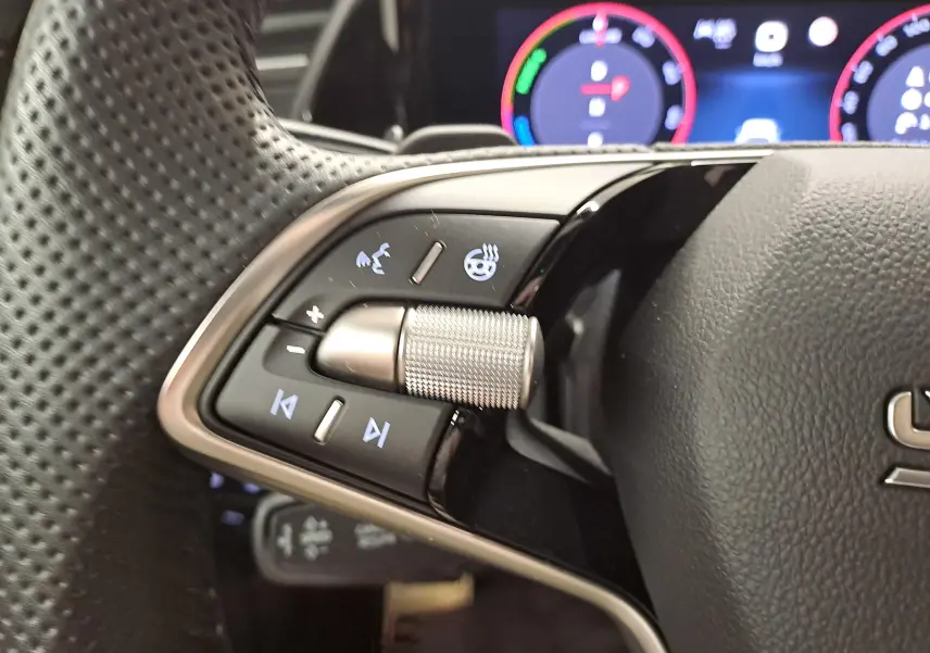 Gros plan sur les commandes gauche du volant perforé du Skoda Kodiaq 2025 avec affichage numérique en arrière-plan.