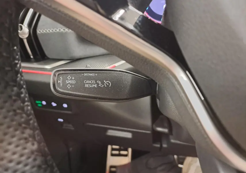 Gros plan sur la commande de régulateur de vitesse au volant d’un Skoda Kodiaq gris graphite, intérieur noir.
