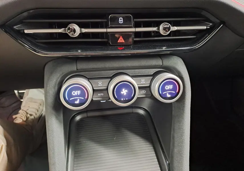 Vue rapprochée des commandes de climatisation du tableau de bord d’un Skoda Kodiaq gris graphite, avec boutons rétroéclairés et aérateurs noirs.