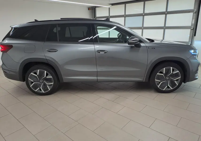 Vue de profil côté gauche d'un Skoda Kodiaq gris graphite avec jantes alliage 20'' et vitres teintées.