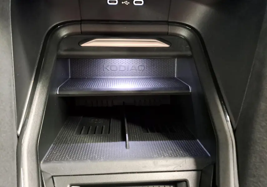 Gros plan intérieur sur le compartiment de rangement noir avec logo KODIAQ et ports USB éclairés du Skoda Kodiaq 2025.