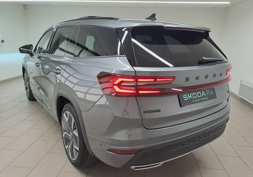Vue 3/4 arrière droite du Skoda Kodiaq gris graphite avec feux arrière LED allumés et jantes alliage 20 pouces.