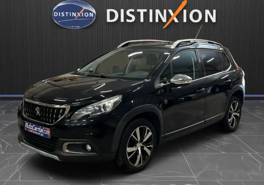 Peugeot 2008 noir en 3/4 avant droit, avec jantes alliage bicolores et barres de toit argentées visibles.
