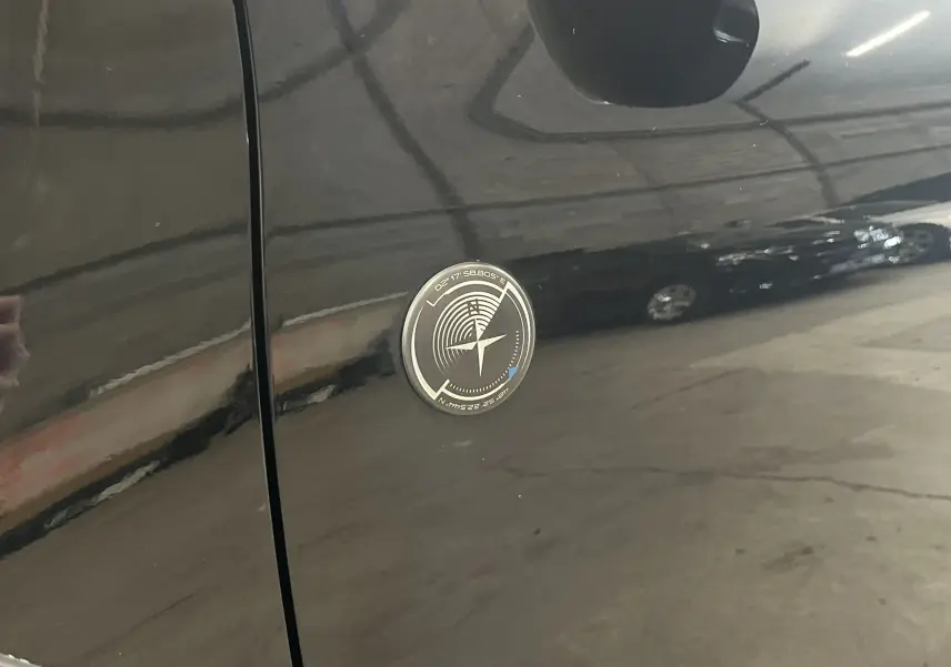 Gros plan sur l’écusson rond noir et argenté sur la porte latérale gauche d’un Peugeot 2008 Crossway noir.