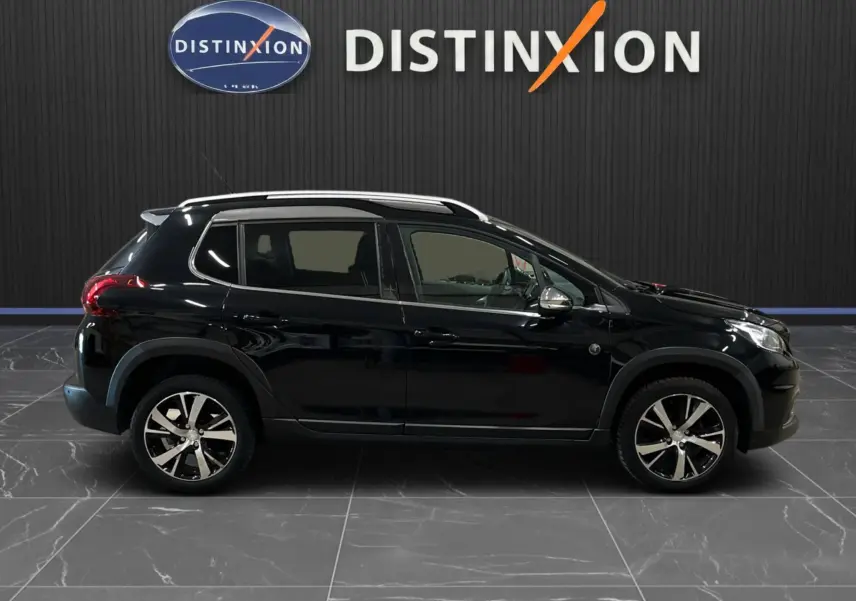 Profil droit d’un Peugeot 2008 Crossway noir de 2018 avec jantes alliage et barres de toit visibles en intérieur showroom.
