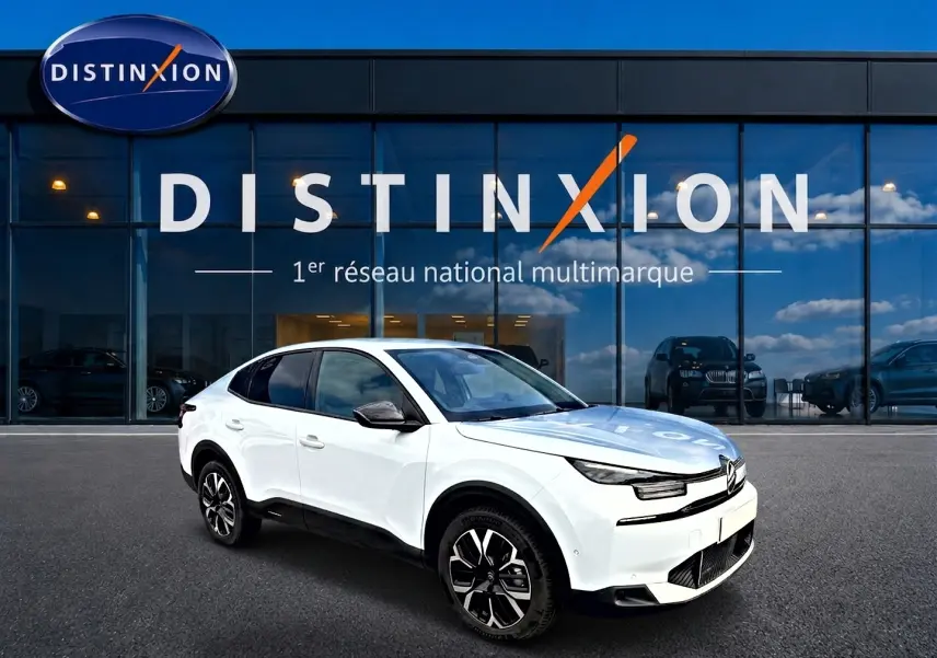 Citroën C4 X blanche vue en 3/4 avant droit, avec jantes alu noires et toit noir contrasté devant showroom Distinxion.
