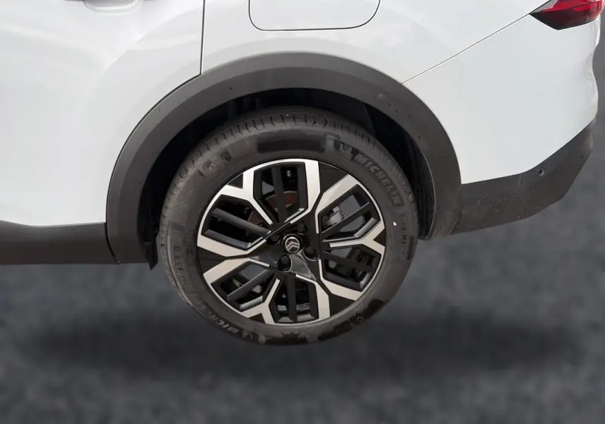 Gros plan sur la roue arrière droite de la Citroën C4 X blanche, avec jante alliage noire et argentée, et feu arrière partiel visible.