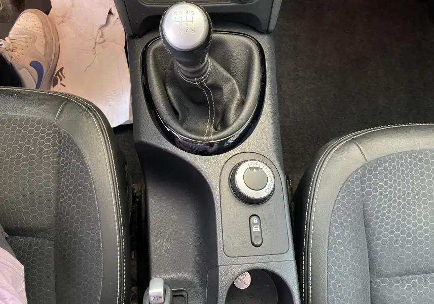 Vue plongeante sur la console centrale du Nissan Qashqai blanc, avec levier de vitesses manuel et sélecteur 4x4.
