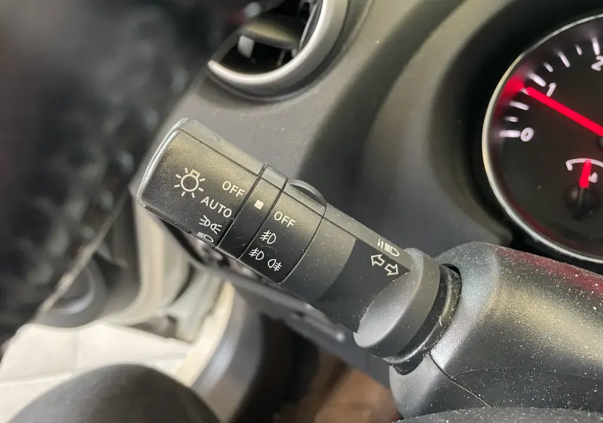 Gros plan sur la manette des feux du Nissan Qashqai blanc 2013, avec commandes d'éclairage et clignotants visibles.
