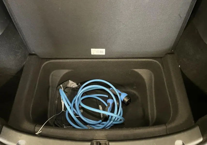 Coffre avant ouvert d'une Tesla Model Y blanc nacré 2022, montrant un câble de recharge électrique bleu enroulé.