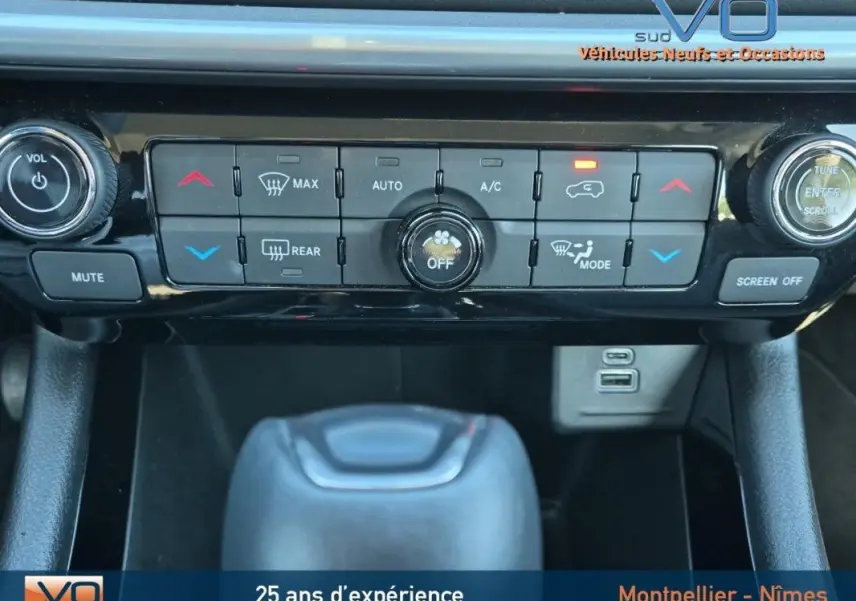 Gros plan sur la console centrale du Jeep Compass gris 2024, montrant commandes climatisation et prises USB.