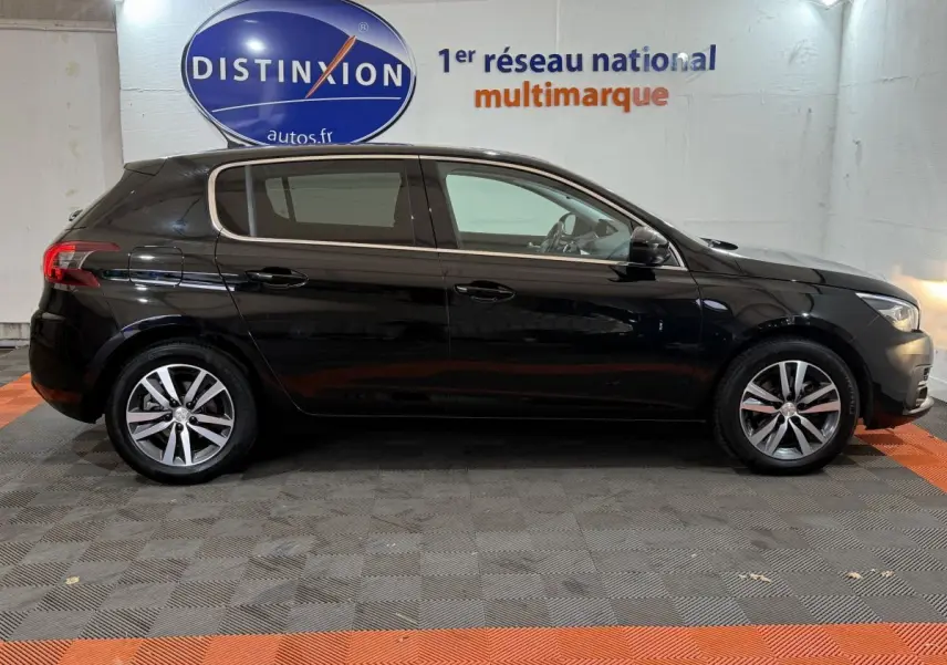 Profil latéral droit d'une Peugeot 308 noire de 2020, avec jantes alliage et vitres teintées, en intérieur showroom.