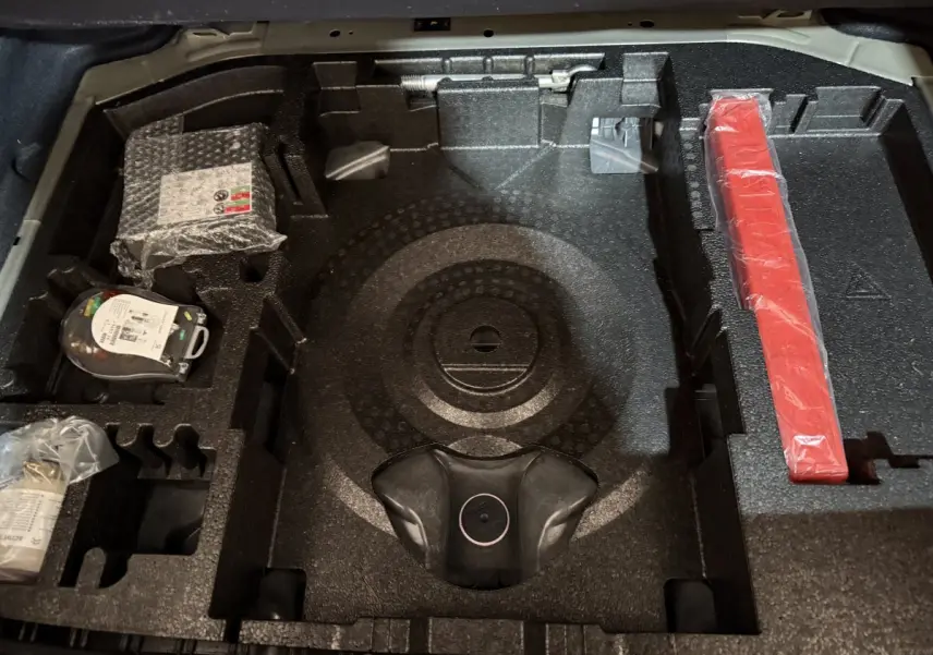 Vue rapprochée du compartiment de rangement sous le plancher de coffre de la Peugeot 308 noir, montrant les accessoires organisés.