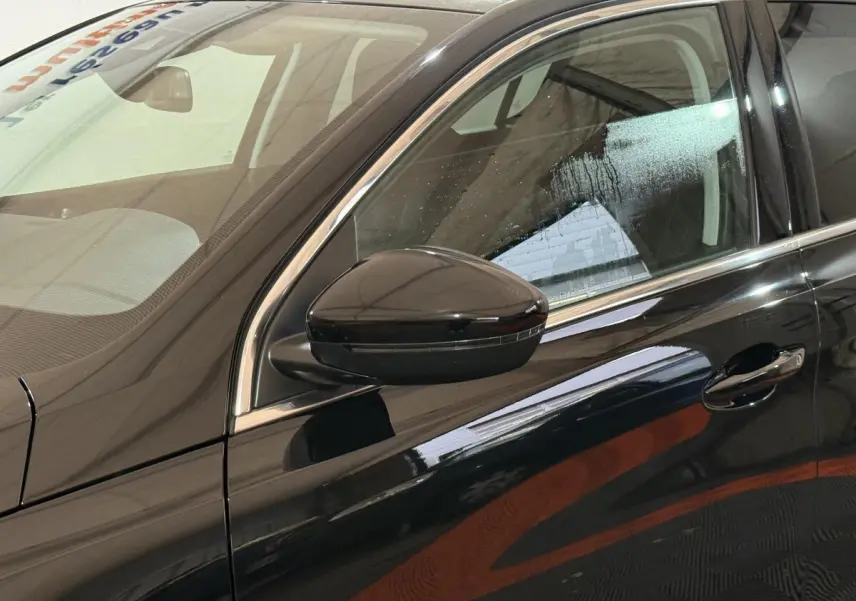 Vue côté gauche rapprochée d'une Peugeot 308 noire 2020, mettant en valeur la portière et le rétroviseur extérieur brillant.