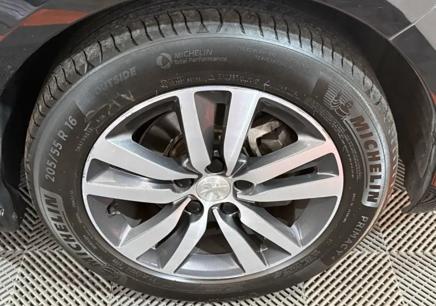 Gros plan sur la roue avant gauche d'une Peugeot 308 noire avec jante alliage et pneu Michelin.