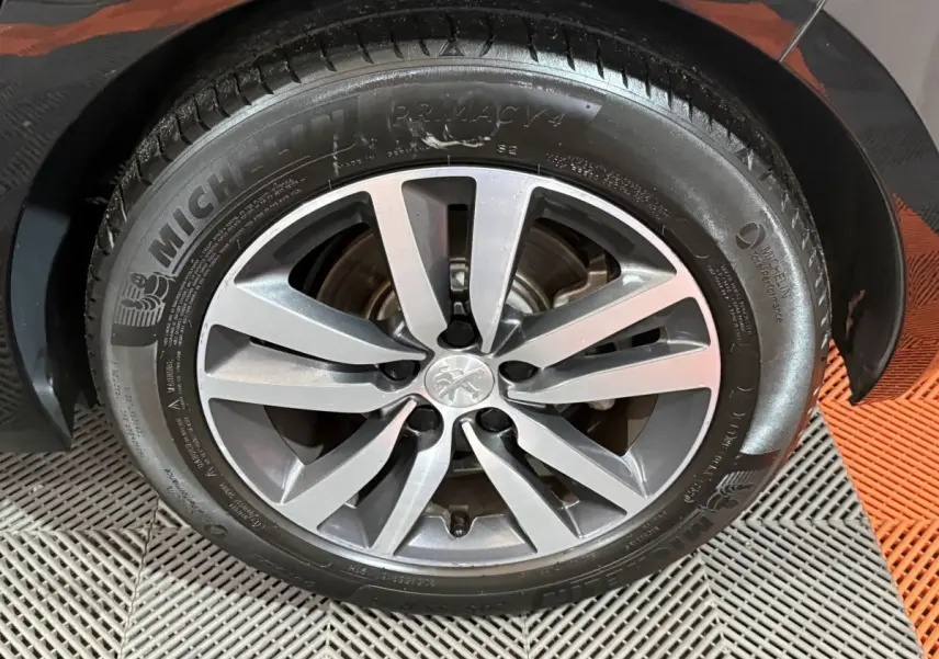 Gros plan sur la roue avant droite d'une Peugeot 308 noire avec jante alliage et pneu Michelin Primacy 4.