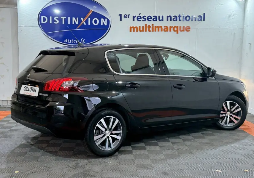 Peugeot 308 noire vue de profil côté droit dans un showroom avec logo Distinxion en arrière-plan.