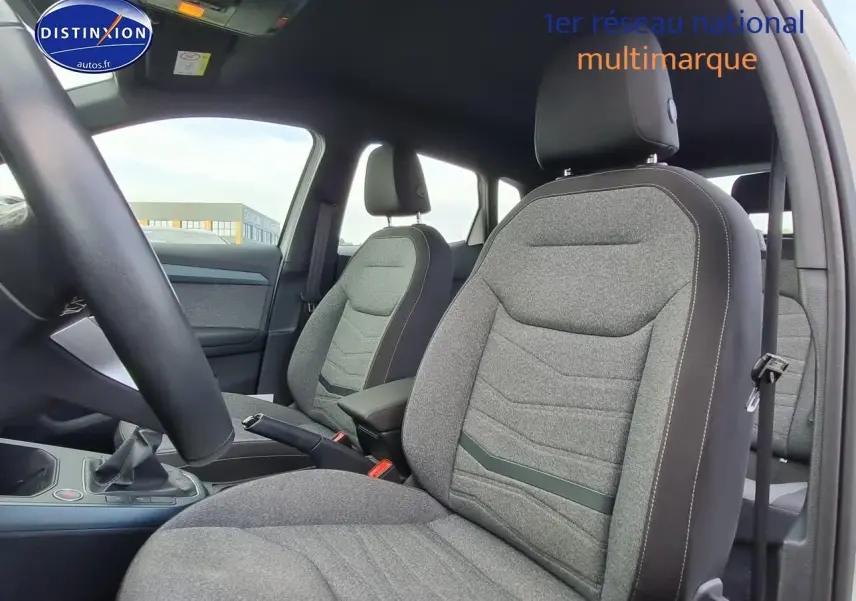 Intérieur de la SEAT Arona 2023 vu côté droit, sièges tissu gris avec coutures contrastées et accoudoir central.