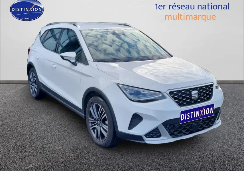 SEAT Arona blanc en 3/4 avant droit, avec jantes alu 17 pouces et barres de toit visibles.