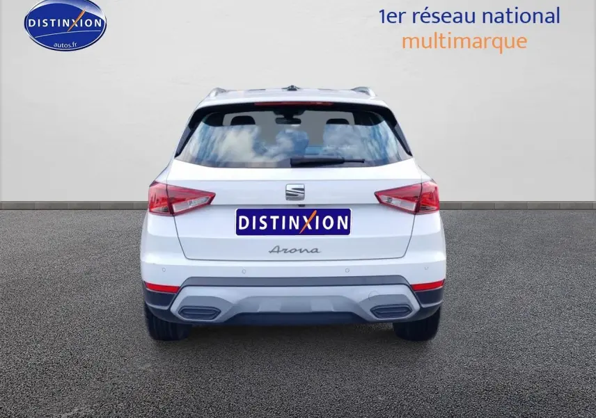 Vue arrière d'un SEAT Arona blanc 2023 avec feux LED et barres de toit visibles sur fond neutre.