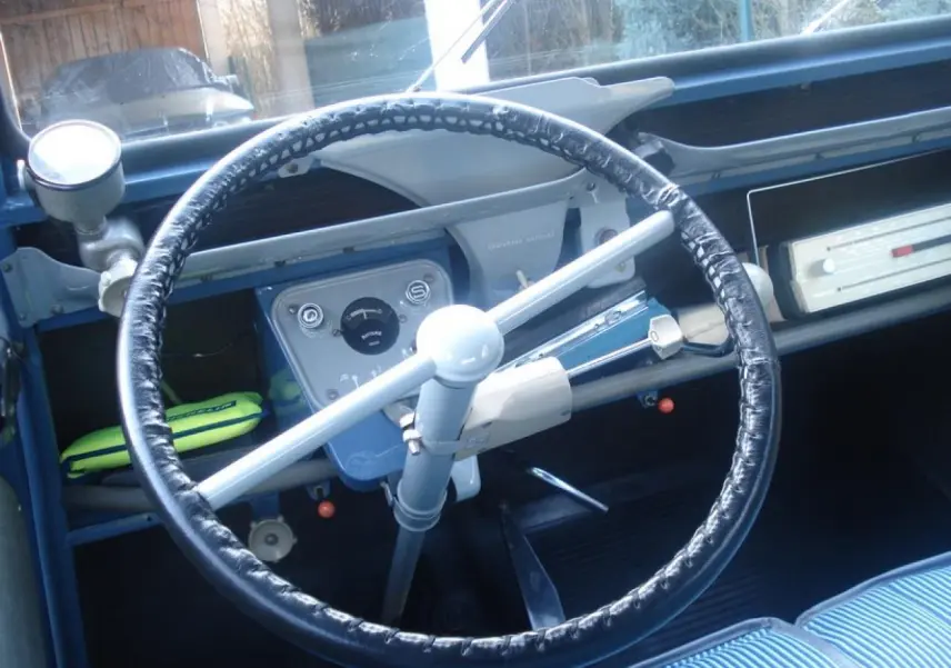Vue intérieure centrée sur le volant noir et le tableau de bord bleu clair de la Citroën 2 CV de 1960.